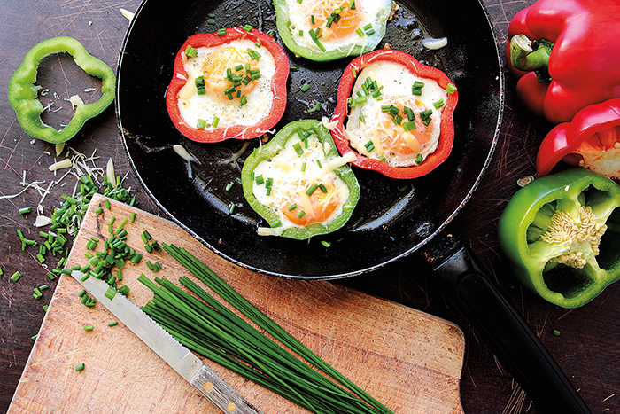 Fried eggs in colorful peppers and green chive for breakfast